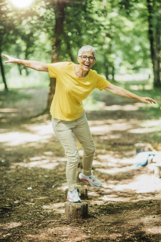 an older adult balancing on one leg on a small piece of wood