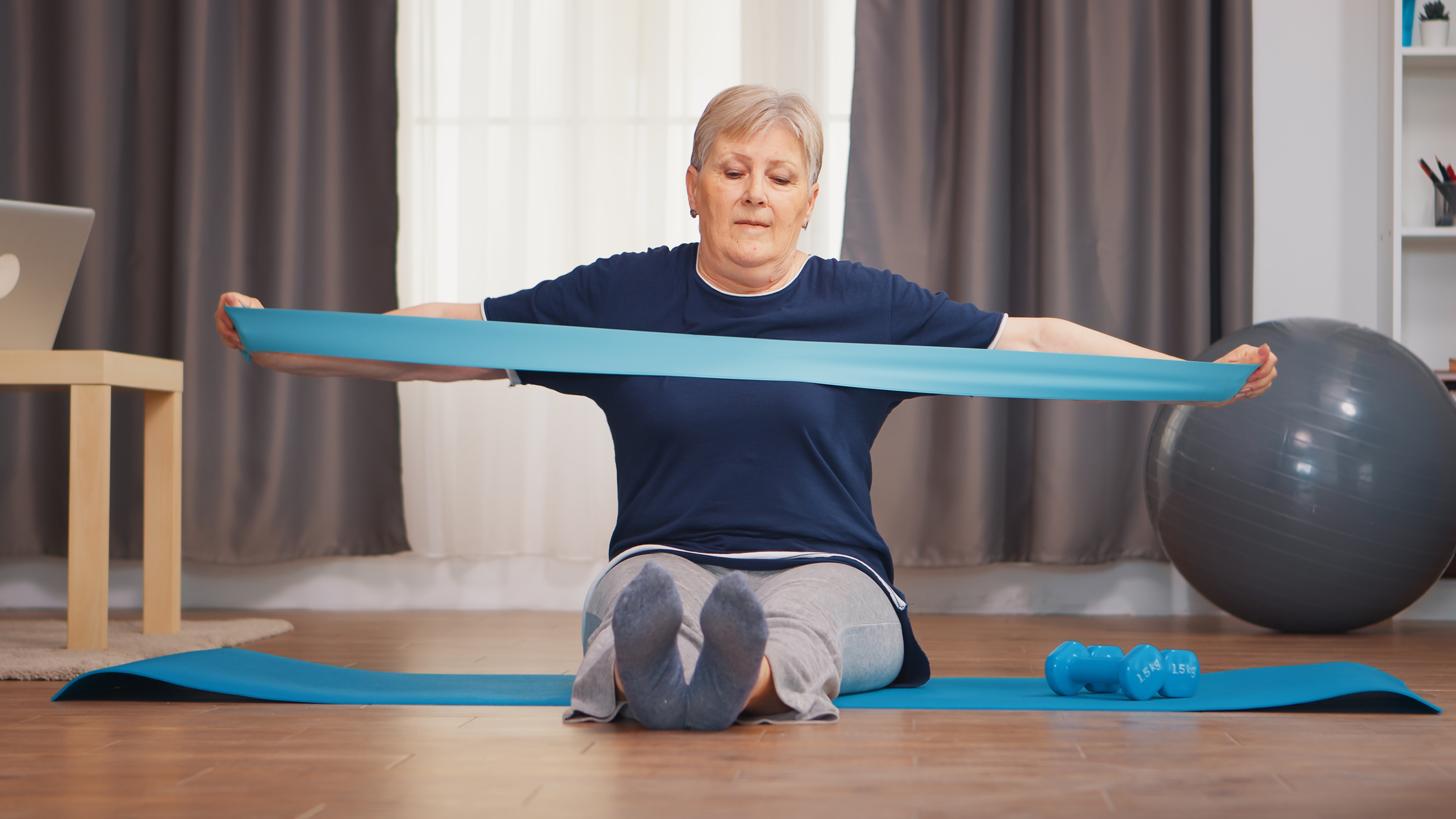 full-length-femal-sitting-on-yoga-mat-stretching-therapy-band